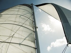 Sailing boat with white sails under a sunny sky, perfect for luxury yacht charter and sailing vacations.